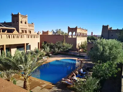 a group of people sitting around a pool at a resort at Auberge Famille Benmoro in Skoura
