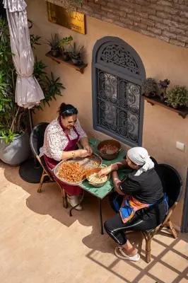 a man and a woman sitting at a table with pizza at Riad Anata in Fès