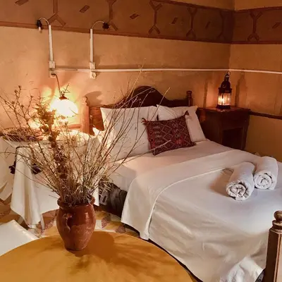 a bedroom with a bed and a vase on a table at Hôtel panoramique de la vallée in Aït Idaïr