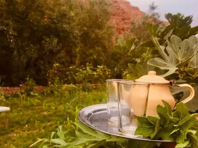 a tea pot and a glass jar on a tray at Hôtel panoramique de la vallée in Aït Idaïr
