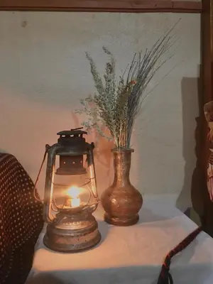 a table with a lantern and a vase on it at Hôtel panoramique de la vallée in Aït Idaïr