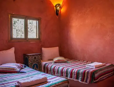 a red room with two beds and a window at Hôtel Chellal ďOuzoud in Ouzoud