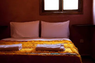 a bed with two towels on it with a window at Hôtel Chellal ďOuzoud in Ouzoud