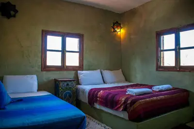 a bedroom with two beds and two windows at Hôtel Chellal ďOuzoud in Ouzoud