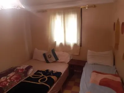 two beds in a small room with a window at Auberge des lacs in Imilchil