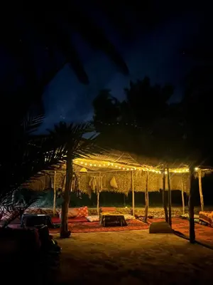 a lit up umbrella on the beach at night at Chez Madani in Mhamid