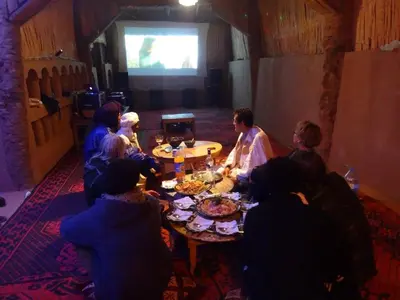 a group of people sitting around a table watching a presentation at Chez Madani in Mhamid