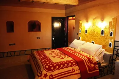 a bedroom with a bed with a red and white blanket at La Kasbah De Dades in Boumalne