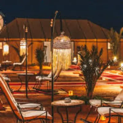 a patio with chairs and a fountain at night at Les Pyramides Luxury desert Camp in Merzouga