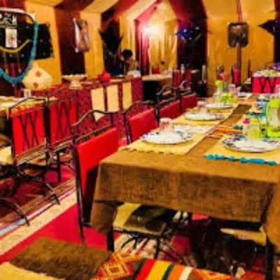 a dining room with long tables and red chairs at Les Pyramides Luxury desert Camp in Merzouga