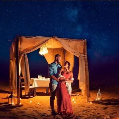 a man and a woman standing in front of a tent at Les Pyramides Luxury desert Camp in Merzouga