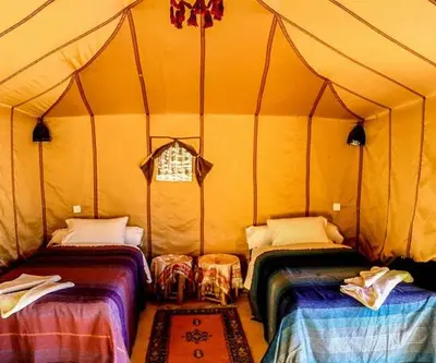 a room with two beds in a tent at Les Pyramides Luxury desert Camp in Merzouga