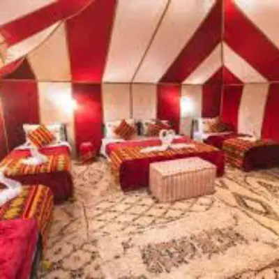 a large room with red walls and couches at Les Pyramides Luxury desert Camp in Merzouga