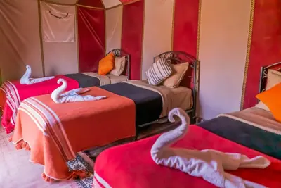 a room with three beds with swans on them at Les Pyramides Luxury desert Camp in Merzouga