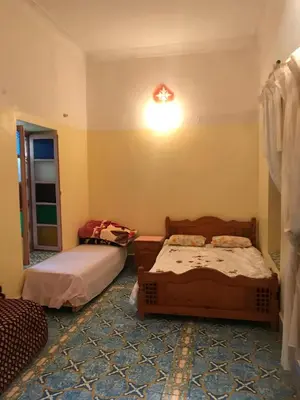 a bedroom with two beds and a light on the wall at Écologie oasis tafilalt CHEZ L' HABITANT in Er Rachidia