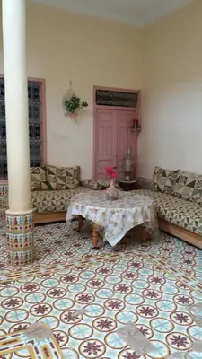 a living room with a table and a pink door at Écologie oasis tafilalt CHEZ L' HABITANT in Er Rachidia