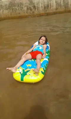 a young girl laying on a raft in the water at Écologie oasis tafilalt CHEZ L' HABITANT in Er Rachidia