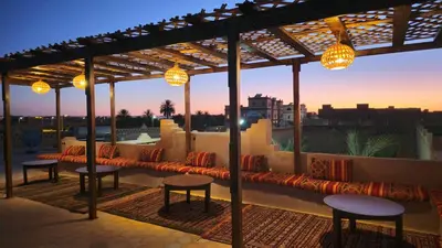 a rooftop patio with tables and chairs and lights at Auberge Les Roches in Merzouga