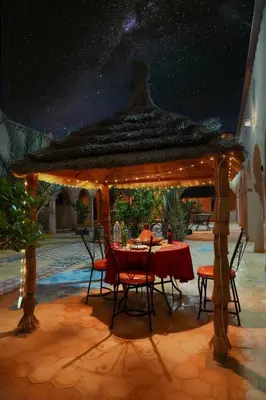 a table and chairs under a gazebo at night at Auberge Les Roches in Merzouga