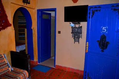 a room with a blue door and a tv at Auberge Les Roches in Merzouga