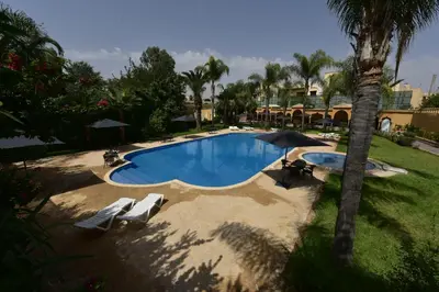 an overhead view of a swimming pool with chairs and an umbrella at Hôtel Fès Inn & SPA in Fès