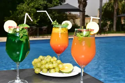 three cocktails on a table next to a plate of fruit at Hôtel Fès Inn & SPA in Fès