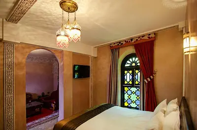 a bedroom with a bed with a window and a chandelier at Palais Ommeyad Suites & Spa in Fès