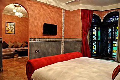 a bedroom with a bed and a couch and a tv at Palais Ommeyad Suites & Spa in Fès