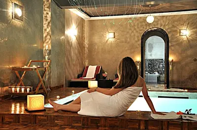 a woman sitting on a table in front of a pool at Palais Ommeyad Suites & Spa in Fès