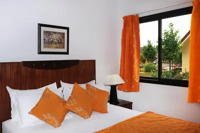 a bedroom with a bed with orange curtains and a window at Farah Inn Ifrane in Ifrane