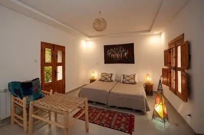 a bedroom with a bed and a table and a chair at Auberge le Maquis in Aghbalou