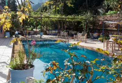 a swimming pool with blue water in a resort at Auberge le Maquis in Aghbalou