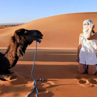 a woman with a camel in the desert at Magic Luxury Camp in Merzouga