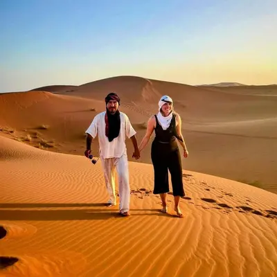a man and a woman walking in the desert at Magic Luxury Camp in Merzouga