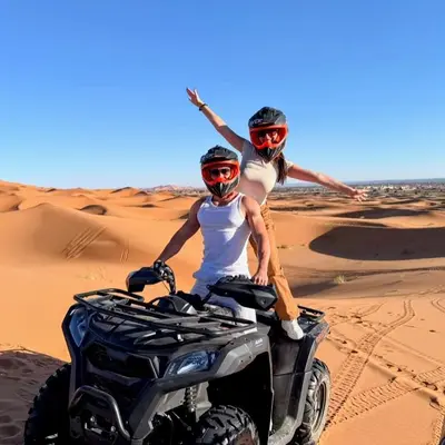 two people riding on a quad bike in the desert at Magic Luxury Camp in Merzouga