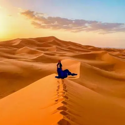 a woman riding a camel in the desert at Magic Luxury Camp in Merzouga