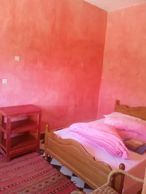 a bedroom with a bed and a side table at Complexe Collier D' Ambre in Imilchil