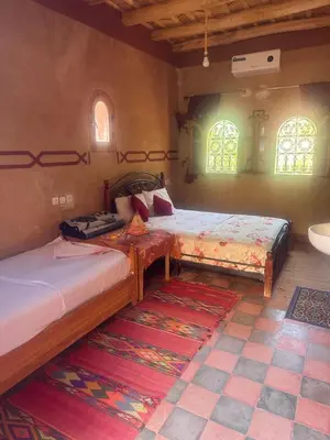two beds in a room with two windows at Auberge Des Jardins du Dades in Boumalne