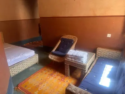 a room with a bed and a chair and a table at Auberge Des Jardins du Dades in Boumalne