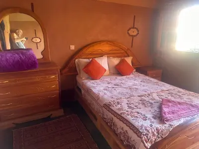 a bedroom with a bed and a dresser and a mirror at Auberge Des Jardins du Dades in Boumalne
