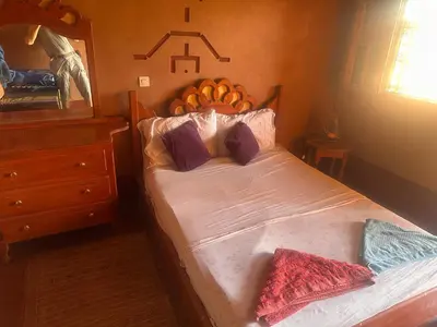 a bedroom with a bed with a wooden head board at Auberge Des Jardins du Dades in Boumalne