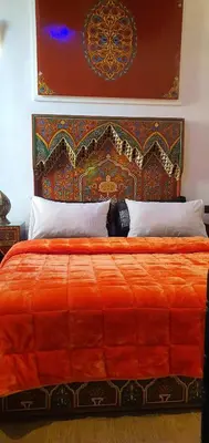 a bed with an orange comforter and pillows at Dar Dahab in Fès