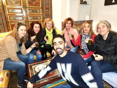a group of women sitting around a man holding wine glasses at Dar Dahab in Fès