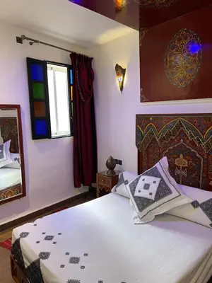 a bedroom with a bed and a mirror and a window at Dar Dahab in Fès