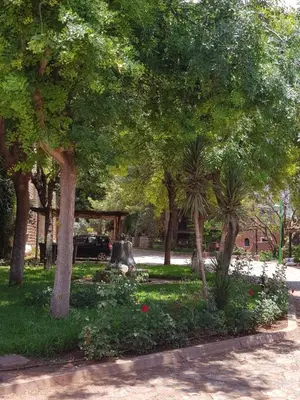a park with trees and flowers and a fountain at Appart Bin Elouidane in Bine el Ouidane