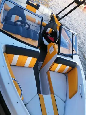 a white boat with orange and white seats on the water at Appart Bin Elouidane in Bine el Ouidane