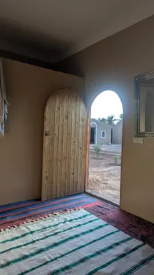 a room with a large wooden door and a rug at Kasbah Desert Camp in Mhamid