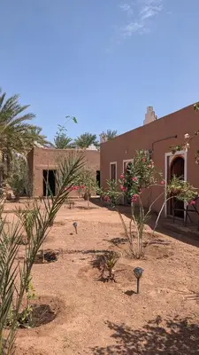 a building in the middle of a desert with plants at Kasbah Desert Camp in Mhamid