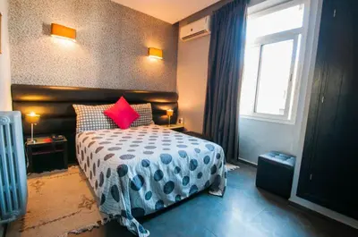 a bedroom with a bed with red pillows and a window at Hotel De La Paix in Fès