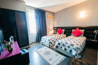 a hotel room with two beds with red pillows at Hotel De La Paix in Fès